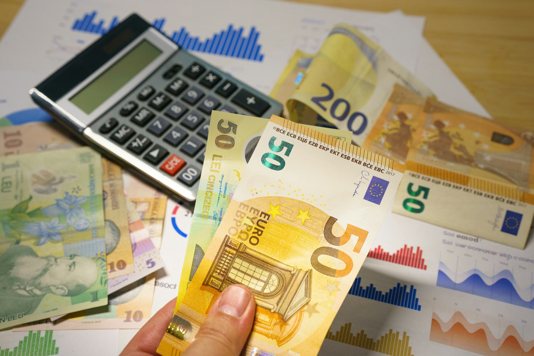 Bancnote în lei și euro lângă un calculator, imagine ilustrativă